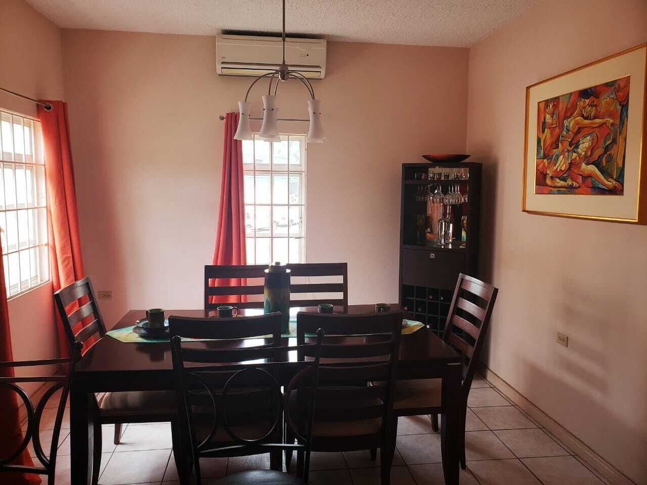 A dining area with a table, chairs, and a cabinet.