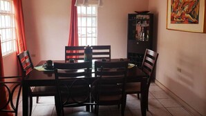 A dining area with a table, chairs, and a cabinet. - Flagstaff Home Away From Home (Port of Spain)