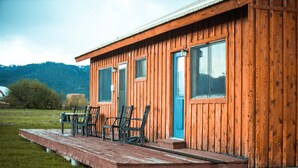 Eine Holzhütte mit Veranda, Sitzgelegenheiten im Freien und Blick auf die umliegende Landschaft.