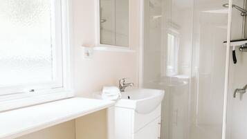 Une salle de bain moderne avec un meuble-lavabo blanc, un évier, un miroir et une cabine de douche en verre.