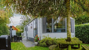 A house with a patio area, a wooden table, and a bench. - Luxury Chalet for Lovers of Peace, Nature (Goedereede)