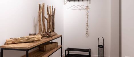 Une pièce au décor minimaliste, avec une table en bois, des étagères, un luminaire suspendu et un radiateur.