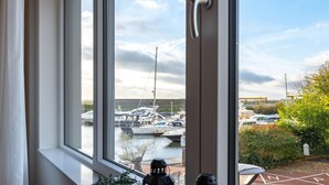 A view of a marina with several boats docked, visible through a window with a door frame. - Luxury Apartment in Kamperland (Kamperland)