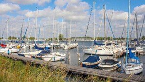 A marina with multiple sailboats docked at wooden piers. - Luxury Apartment in Kamperland (Kamperland)
