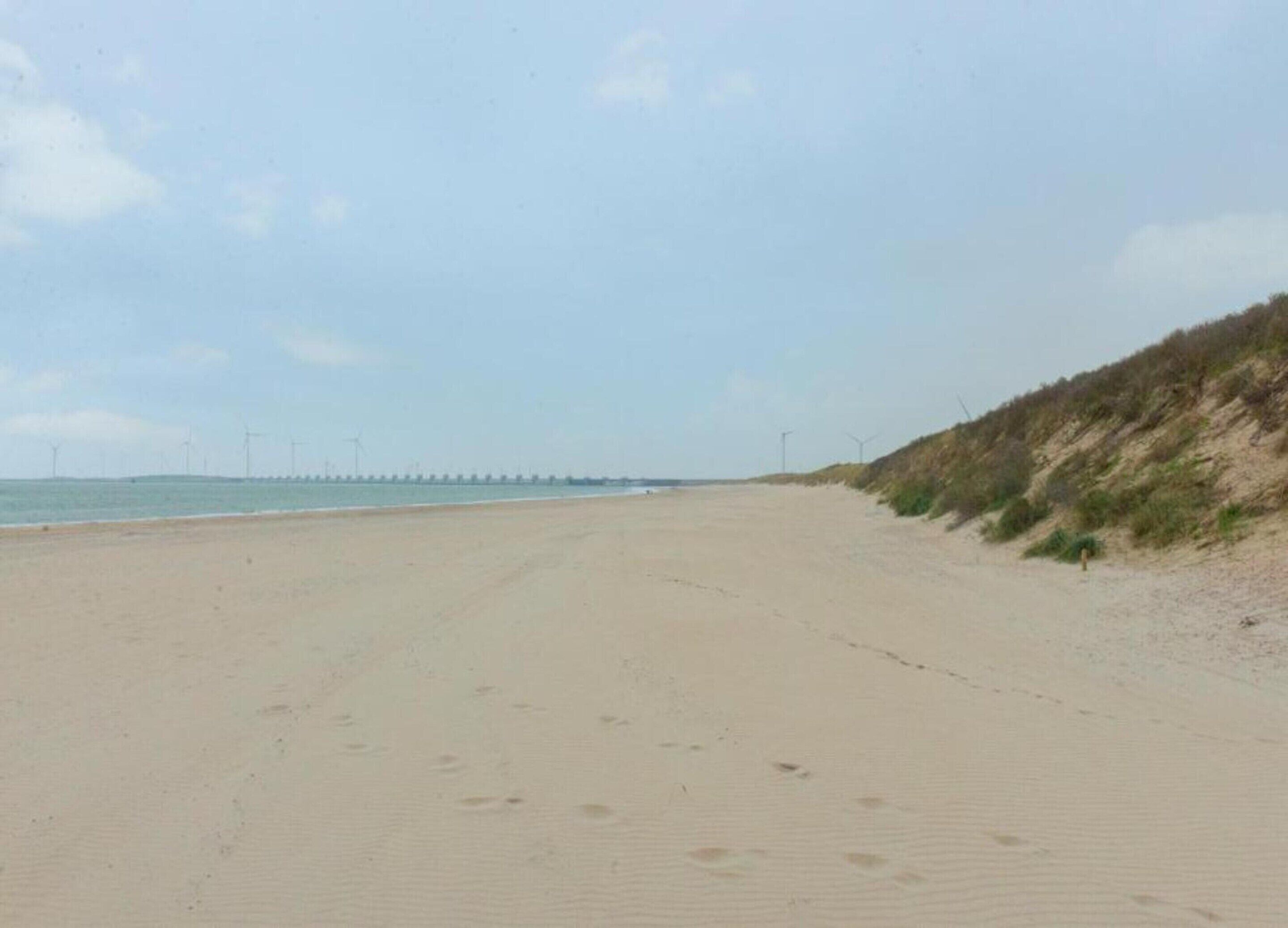 A wide sandy beach with a gentle slope leading to the sea.