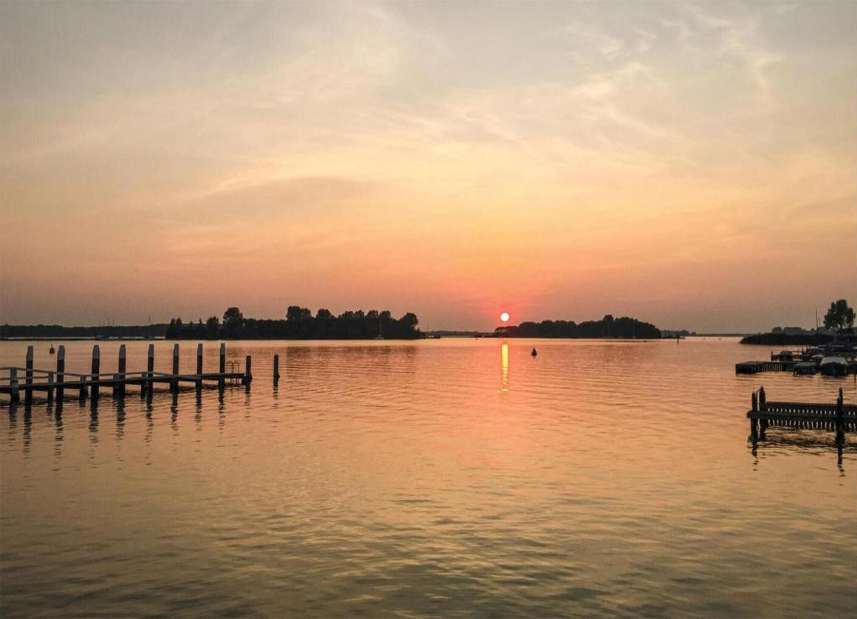 A calm lake at sunset with a wooden dock extending into the water.