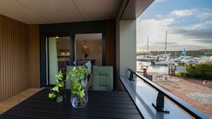 A balcony with a view of a marina, a potted plant, and a seating area with cushions. - Luxury Apartment in Kamperland (Kamperland)