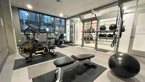 Une salle de sport équipée de matériel d’exercice, d’un banc, d’un grand ballon d’exercice et d’un porte-poids.