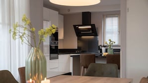 A modern kitchen with a central island, built-in oven, and a black range hood. - Villa in Zeeland With Jacuzzi and Sauna (Colijnsplaat)