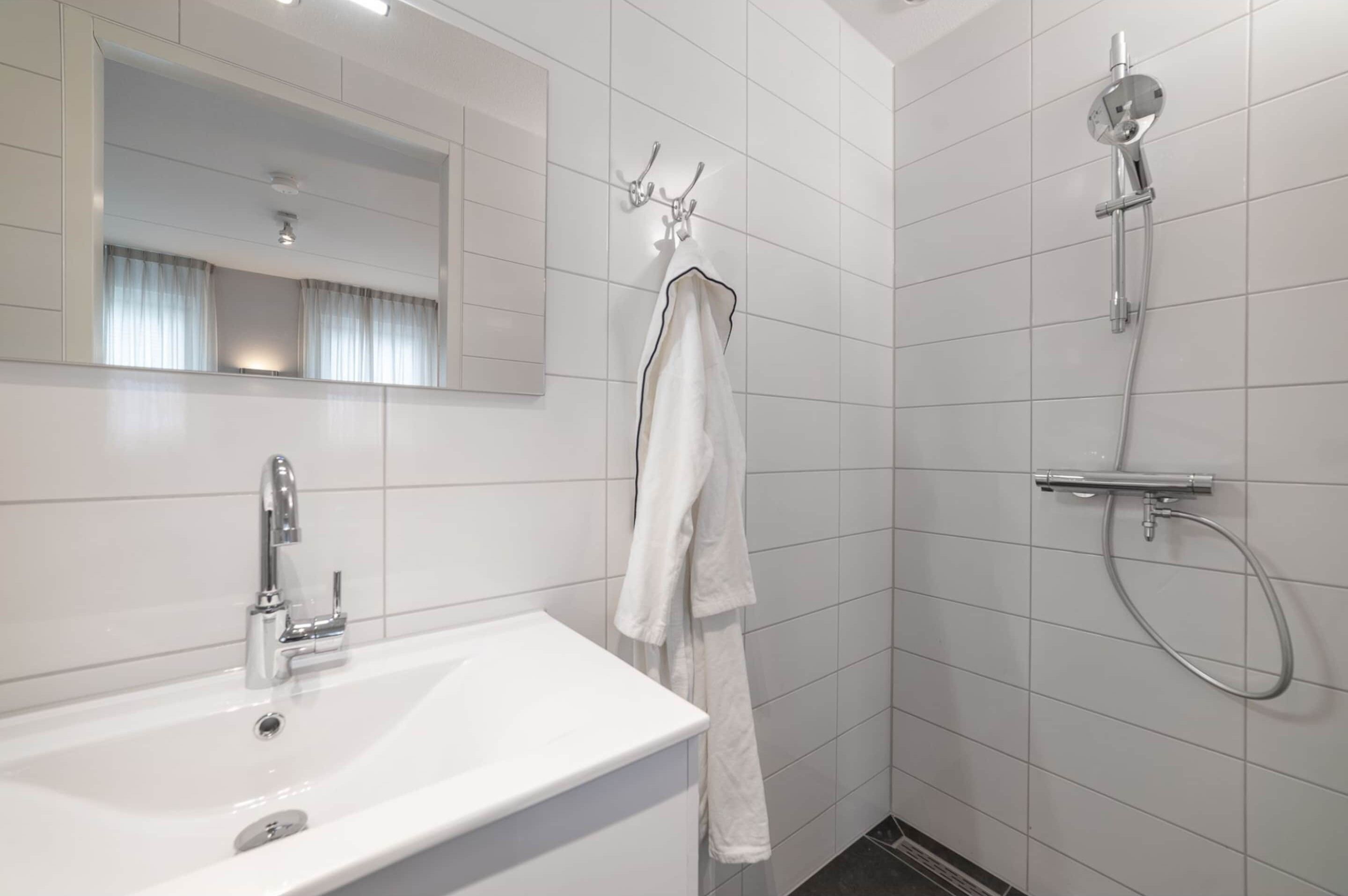A modern bathroom with a white sink, a mirror, and a shower.