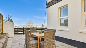 Eine Terrasse mit Korbmöbeln und einem Tisch, mit Blick auf eine schöne Landschaft.