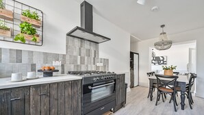 Eine moderne Küche mit Kochinsel, integriertem Backofen und Essbereich mit einer Pendelleuchte.