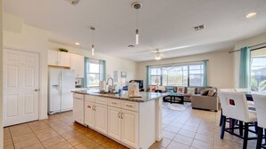 A spacious kitchen with white cabinets, a central island, and a dining area with a sofa and chairs.