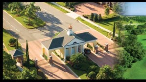 A large, modern building with a symmetrical facade, a central entrance with a portico, and a well-maintained lawn and driveway.