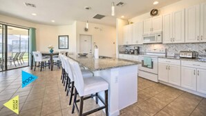 A spacious kitchen with white cabinets, a granite countertop, and a large island with bar stools.