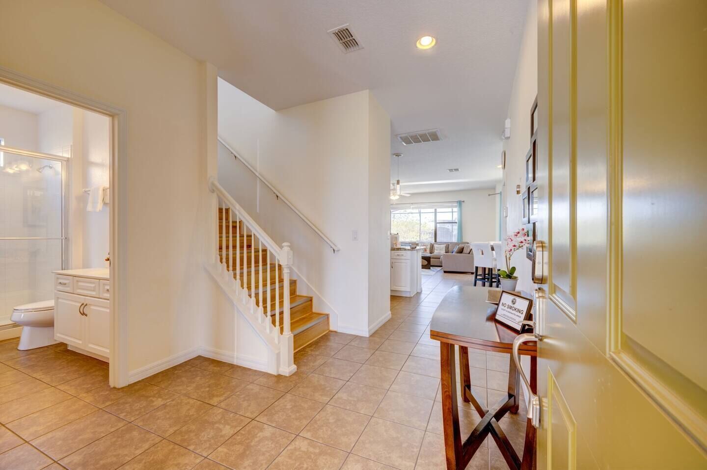 A spacious, well-lit home with a staircase leading to a second floor, a kitchen area, and a living space with a dining table.