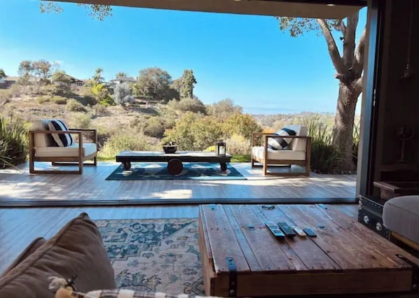 Relax in this serene space with a sofa, coffee table, and bench, offering a view of the surrounding landscape through the large glass door.