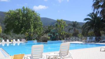 A pool area with lounge chairs and a view of mountains.