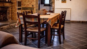 Een eethoek met een betegelde vloer, houten stoelen, een tafel met een geruit tafelkleed en een mand met brood.