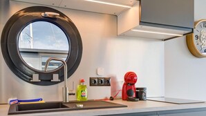 Eine moderne Küche mit rundem Spiegel, Edelstahlspüle und Kaffeemaschine.