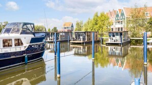 Ein Kanal mit vertäuten Booten und traditionellen Häusern mit Giebeln.