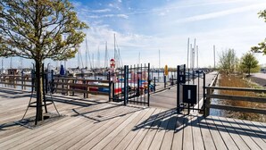 Eine Holzstege mit Blick auf Boote und einen Leuchtturm.