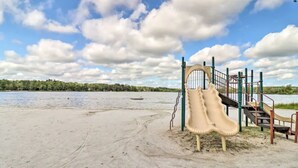 Un parque infantil con tobogán y escaleras cerca de un lago.