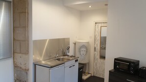 A compact kitchen with a stainless steel sink, a dishwasher, a marble-patterned toilet, and a black toaster oven. - Studio 2 - 3 min from Futuroscope - 1 to 4 people (Chasseneuil-du-Poitou)