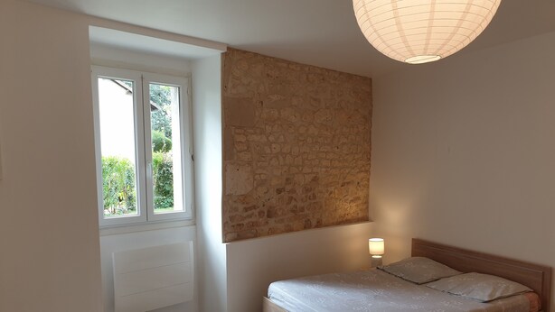 A bedroom with a bed, a window, a wall-mounted light, and a radiator. - Studio 2 - 3 min from Futuroscope - 1 to 4 people (Chasseneuil-du-Poitou)