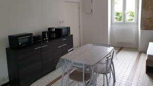A small, modern kitchen with a dining table and chairs, a coffee maker, and a microwave. - Studio 2 - 3 min from Futuroscope - 1 to 4 people (Chasseneuil-du-Poitou)