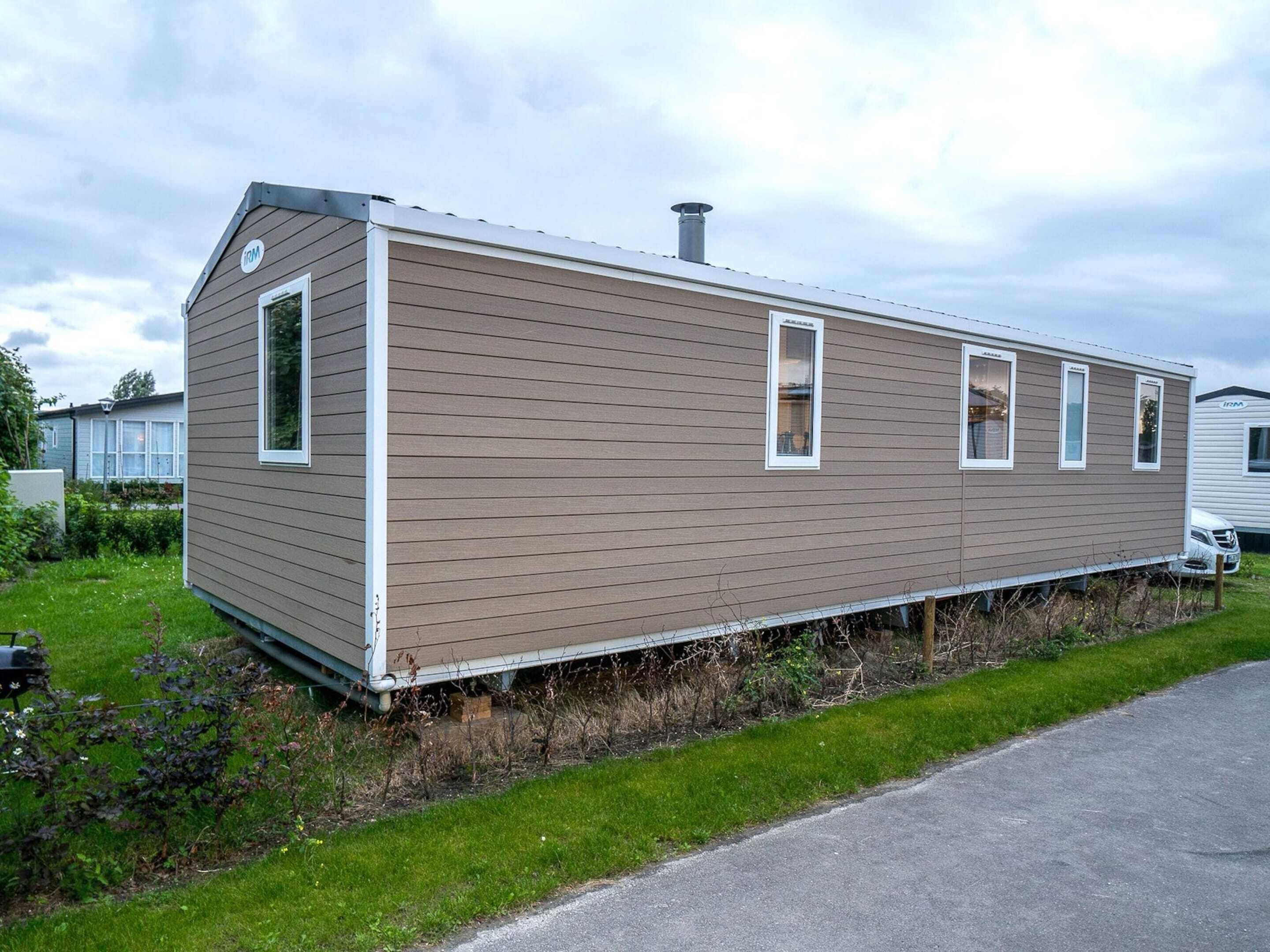 Ett enplanshus på hjul med ett sadeltak, en skorsten och en liten veranda.