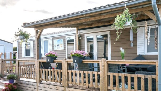 A wooden deck with a railing, potted plants, and outdoor furniture. - Chalet in Oostkapelle Near Beach & Pool (Oostkapelle)
