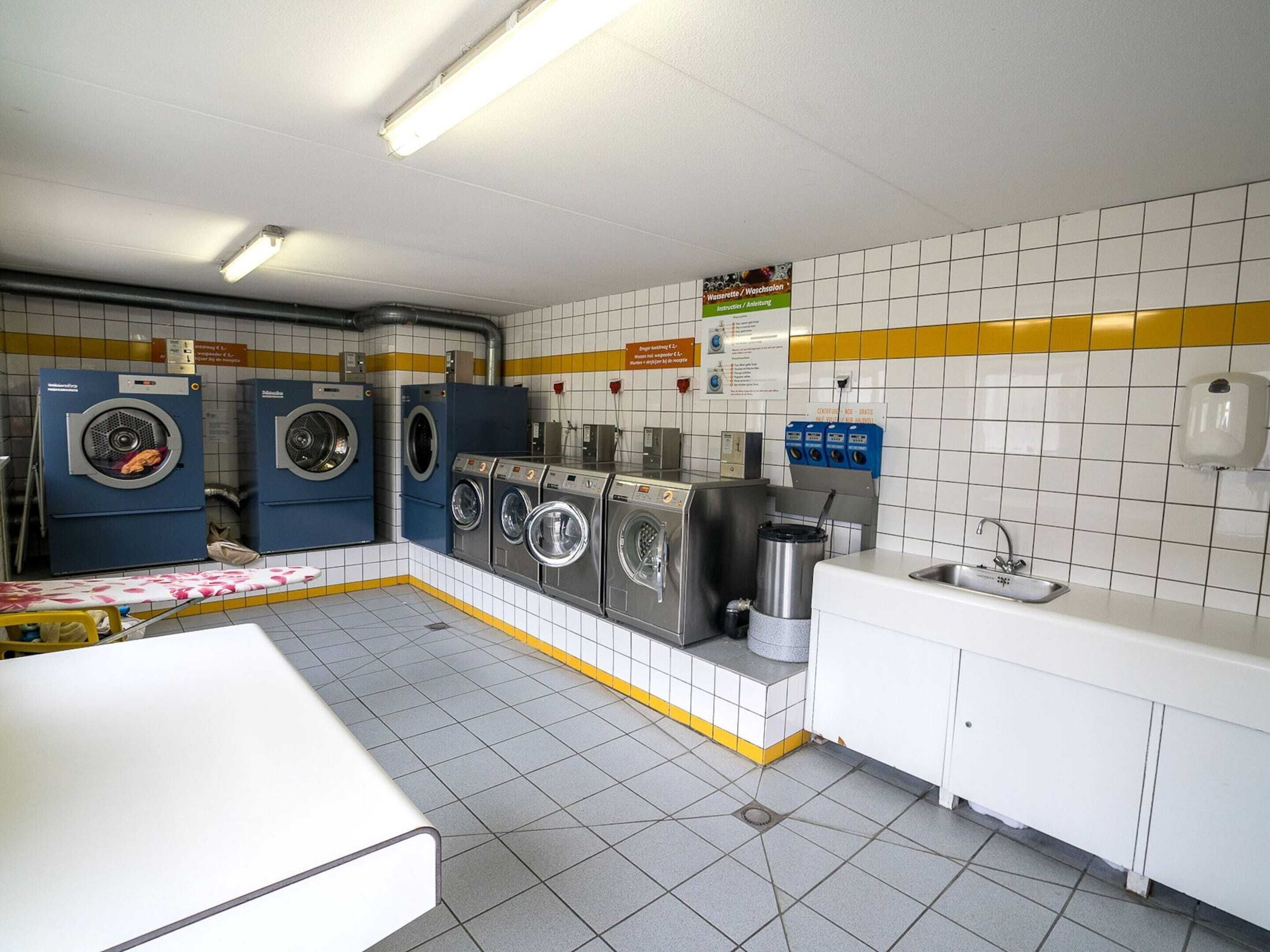 A laundry room with multiple washing machines, a sink, and a drying rack.