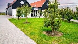 A modern building with a black and white facade, a red roof, and a paved walkway leading to it. - Chalet in Oostkapelle Near Beach & Pool (Oostkapelle)