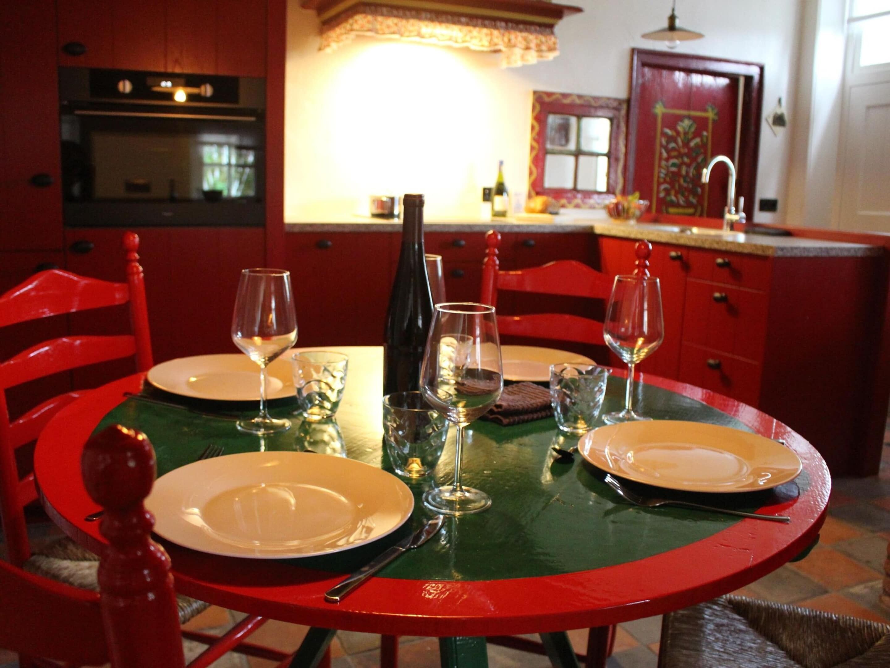 Een eethoek met een groene tafel, rode stoelen en een rode kast op de achtergrond.