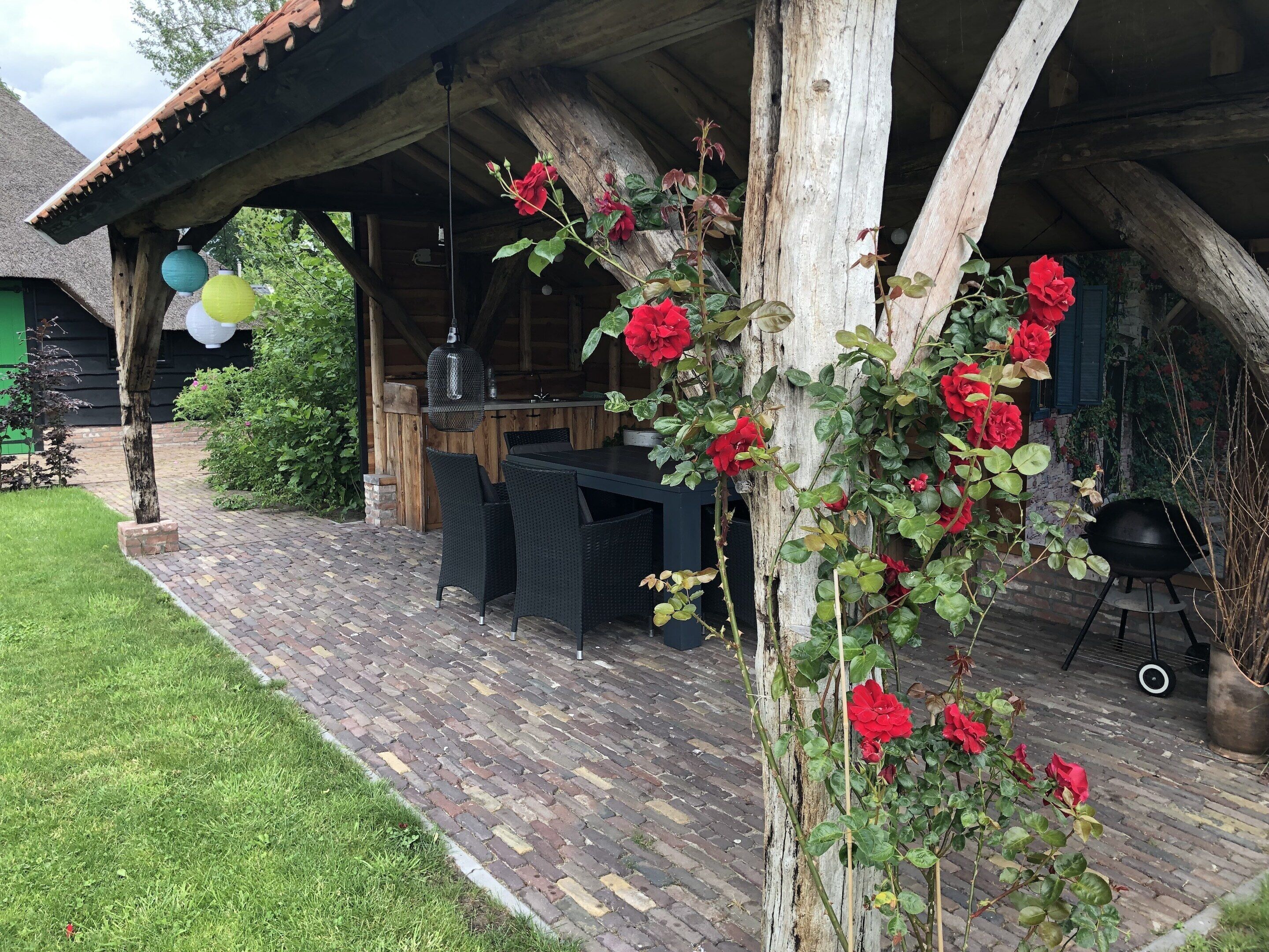Eine rustikale Holzhütte mit einer Ziegelterrasse, einem Esstisch und Stühlen.