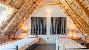A room with two beds, wooden beams, and a sloped ceiling. - Farmhouse in Staphorst With Sauna (Rouveen)