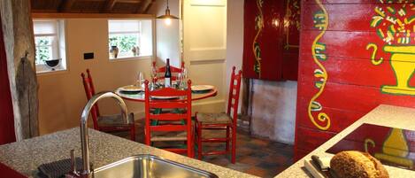 Una cocina con encimeras de granito, un fregadero de acero inoxidable, sillas rojas y una mesa de comedor con sillas.
