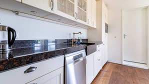 A modern kitchen with white cabinetry, a stainless steel dishwasher, and a granite countertop.