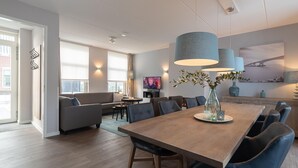 Uma sala de jantar moderna com uma mesa de madeira, cadeiras estofadas em azul e iluminação pendente.