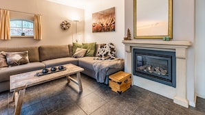Una sala de estar con sofá, mesa de centro, chimenea y un espejo grande.