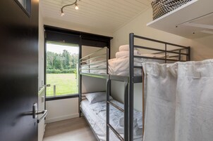 Habitación con literas, una ventana, una puerta y una lámpara en el techo.