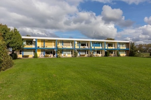 A multi-story motel with a flat roof, a large lawn in front, and a clear sky. - Apartment in Vlissingen Near Sandy Beach (Vlissingen)