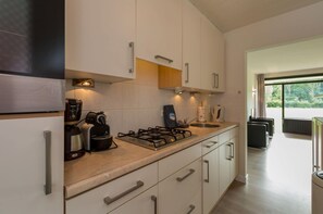 A modern kitchen with white cabinets, a gas stove, and a coffee machine.