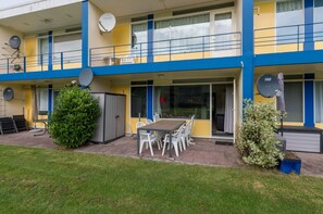 A two-story building with a balcony, satellite dishes, and a patio area with a table and chairs. - Apartment in Vlissingen Near Sandy Beach (Vlissingen)