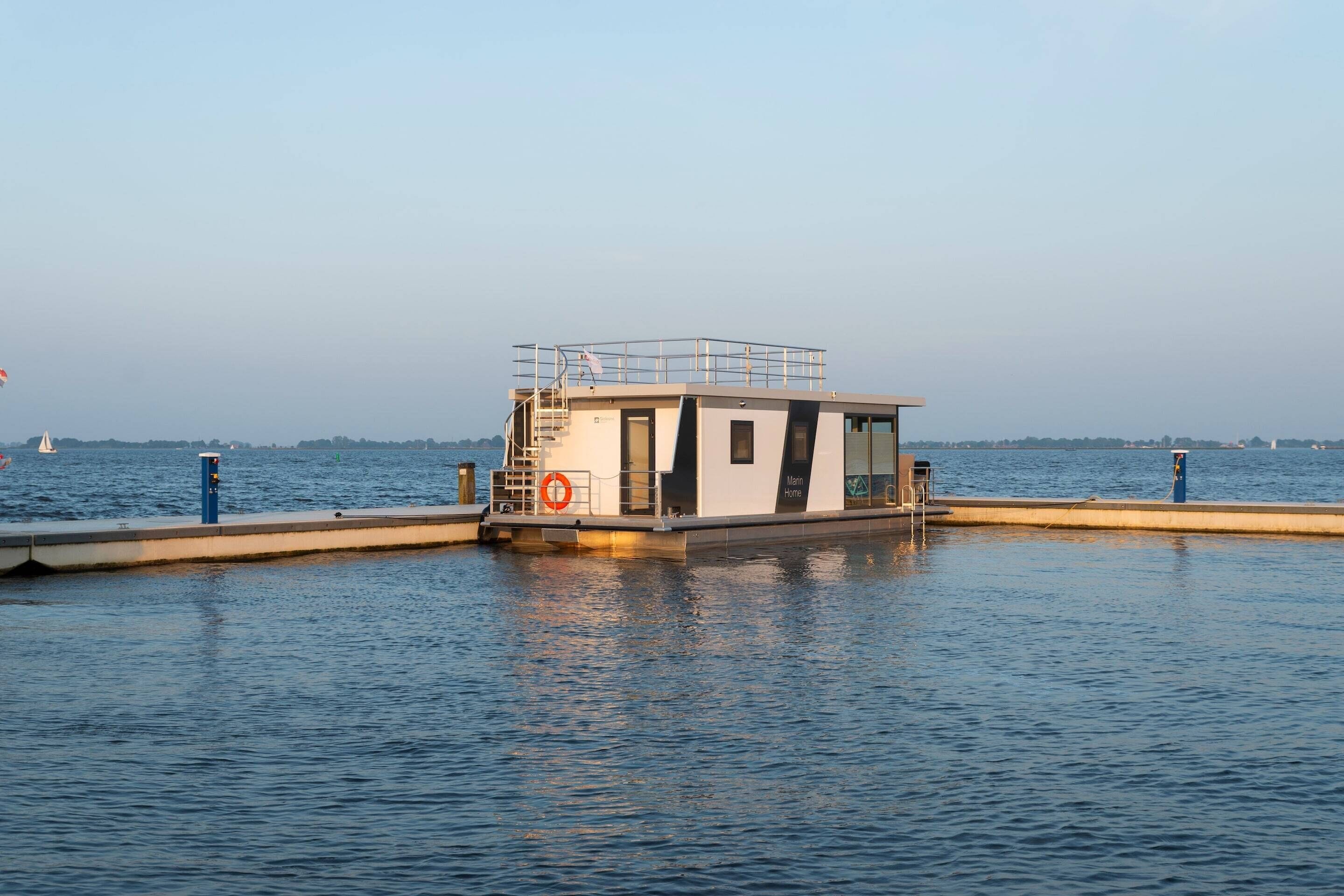 A stationary boat with a lifebuoy and railing, docked at a pier.