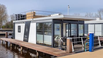 Enjoy waterfront views from the large windows of this compact houseboat, featuring a deck with a bench and table.