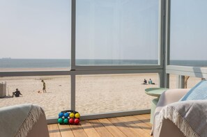 A beach view from a room with large windows, a wooden deck, and a small table. - House in Dishoek With Sea Views (Koudekerke)