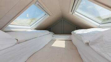 A room with two beds, skylights, and a sloped ceiling.