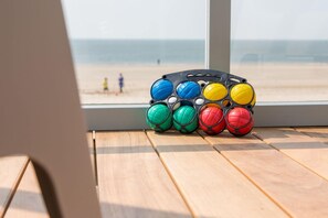 A beach view through a window with a wooden deck and colorful balls. - House in Dishoek With Sea Views (Koudekerke)